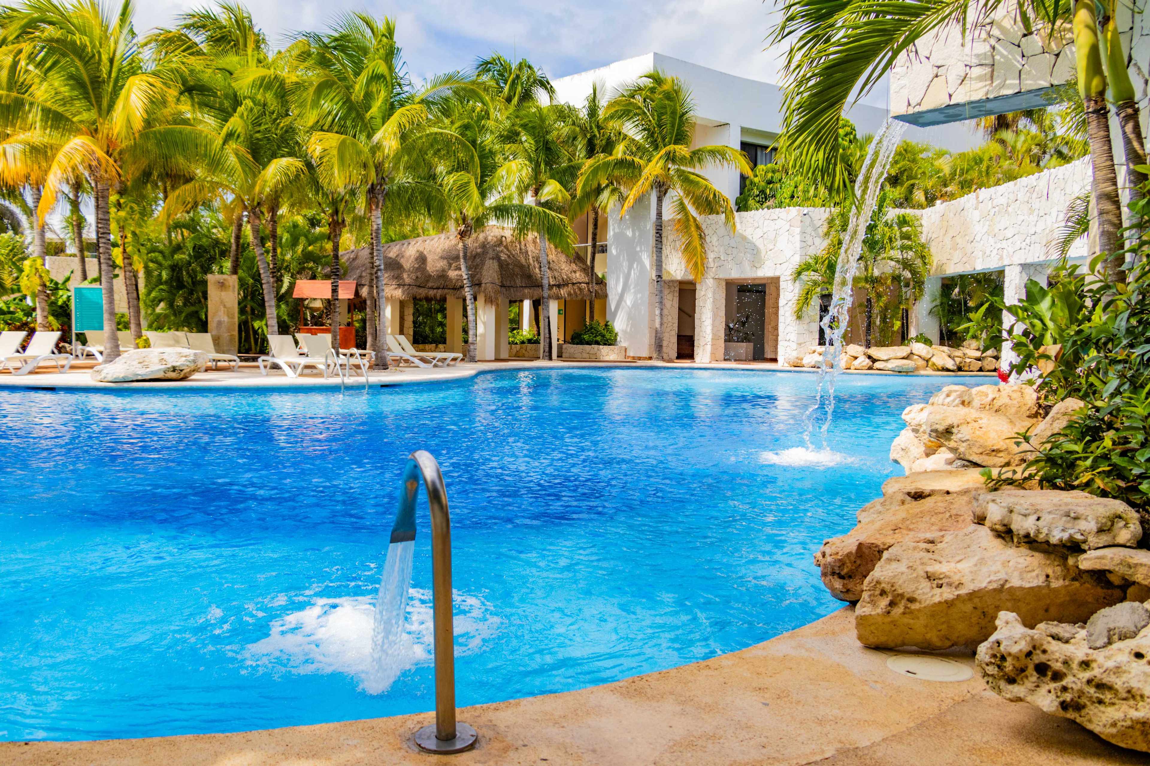 Swimming pool with lounge chairs and cocktails in bar at Hotel Grand Oasis Tulum